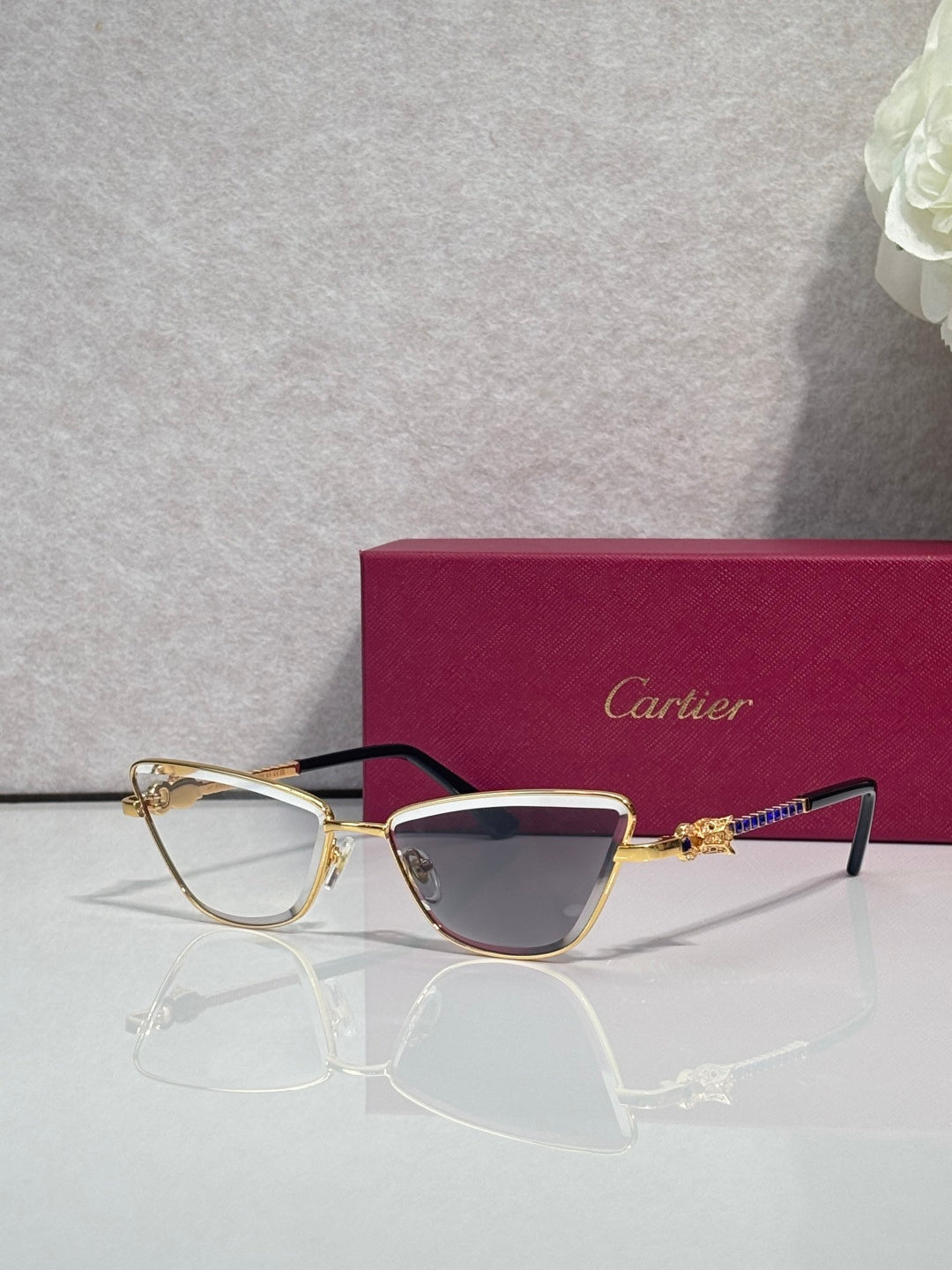 Cat-eye glasses with black and gold frame, tinted lenses and decorative gold temple details