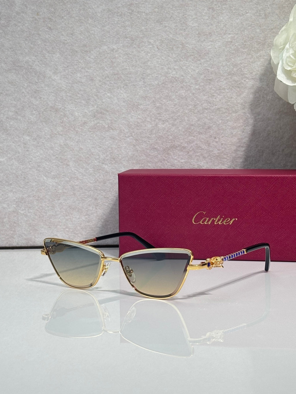 Cat-eye glasses with black frame and gold-tone temples, tinted lenses and decorative hinge detail