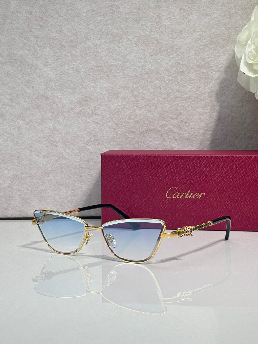 Cat-eye glasses with black frame and gold-tone temples, blue-tinted lenses, ornamental temple detail