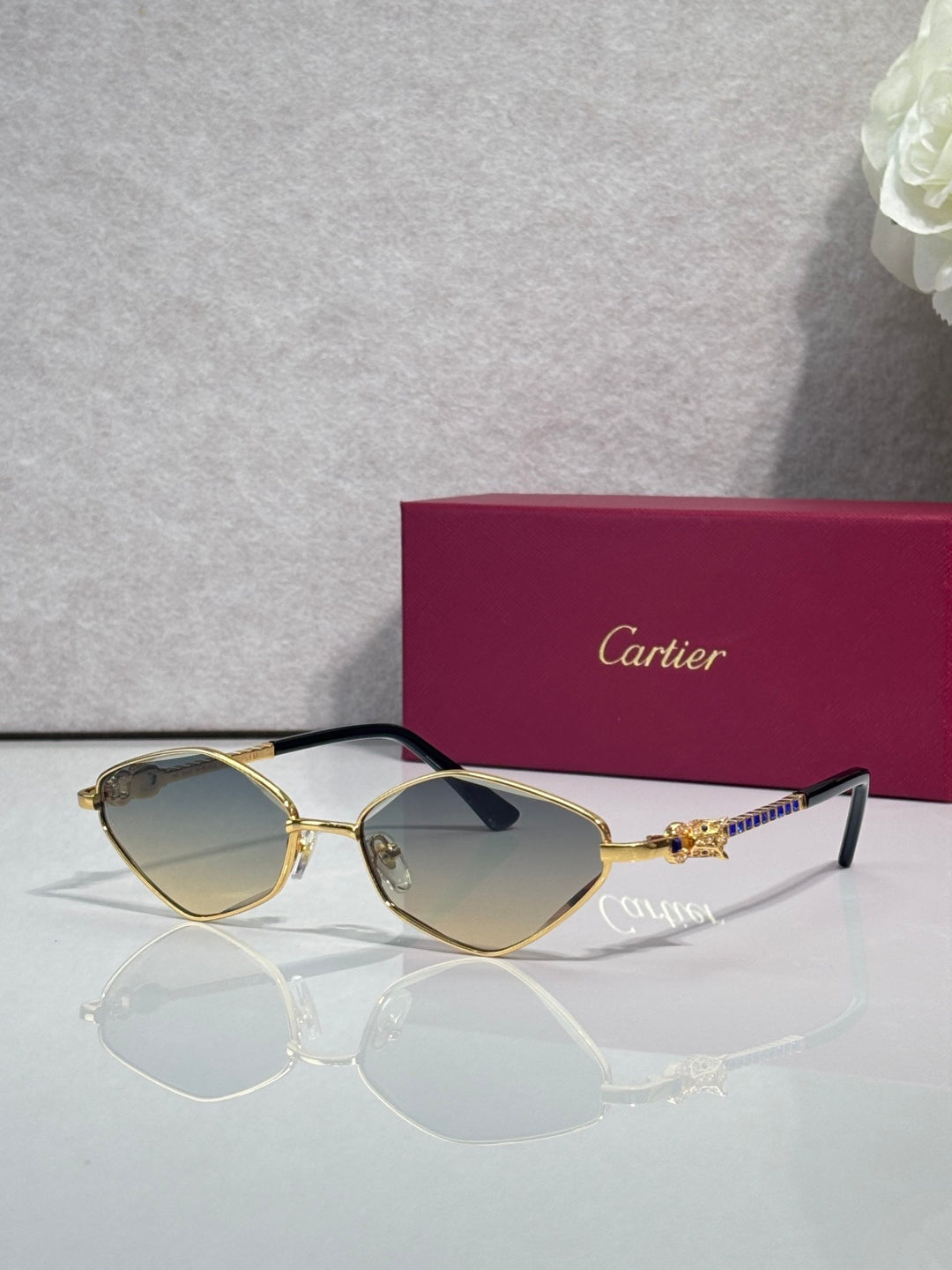 Cartier glasses with gold-tone frame, light gray lenses, and black temple tips.
