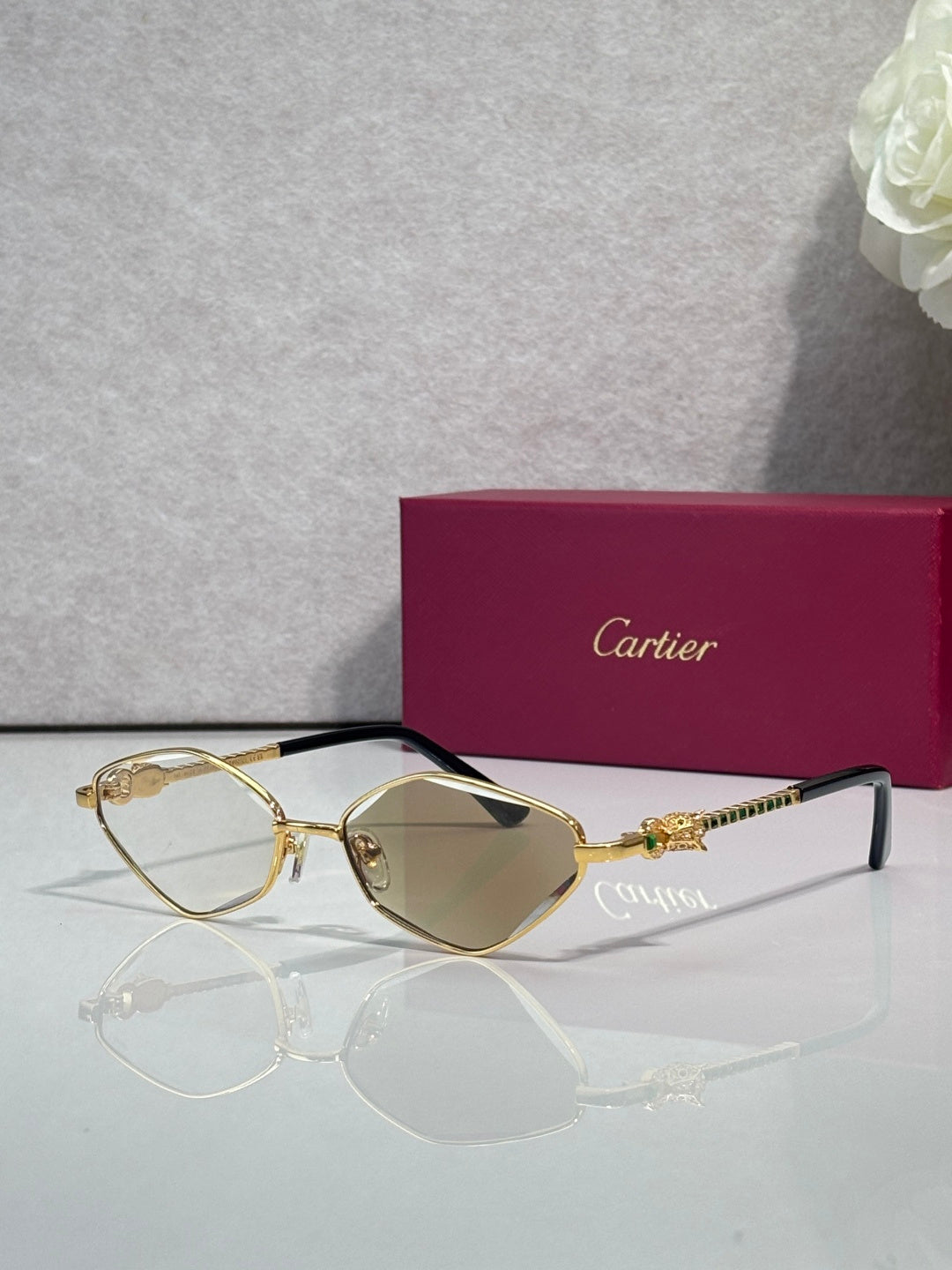 Cartier glasses with gold-tone frame, gray lenses, and blue temple detail.