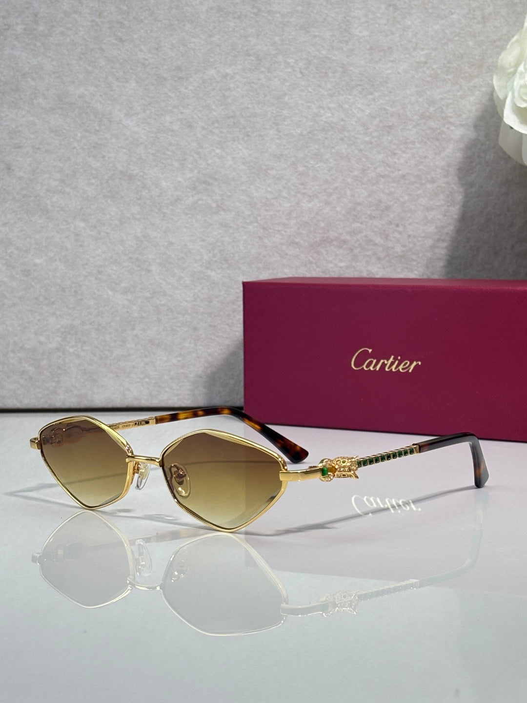 Cartier glasses with gold-tone frame and amber-tinted lenses, gold temple detail.