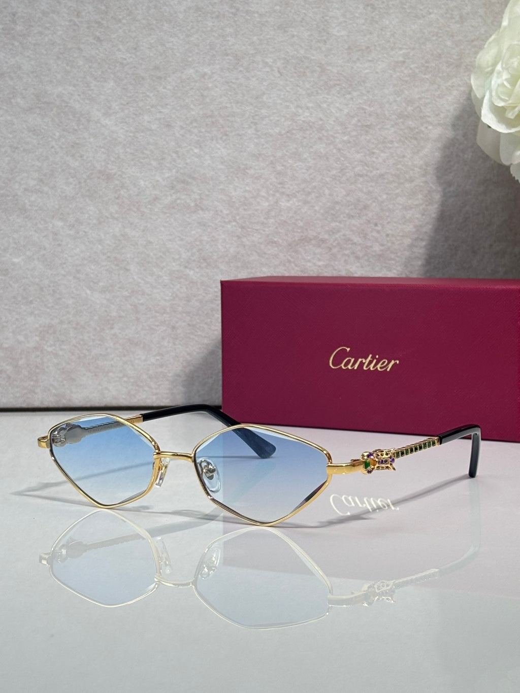 Cartier glasses with gold-tone frame, blue lenses, and black temple tips.