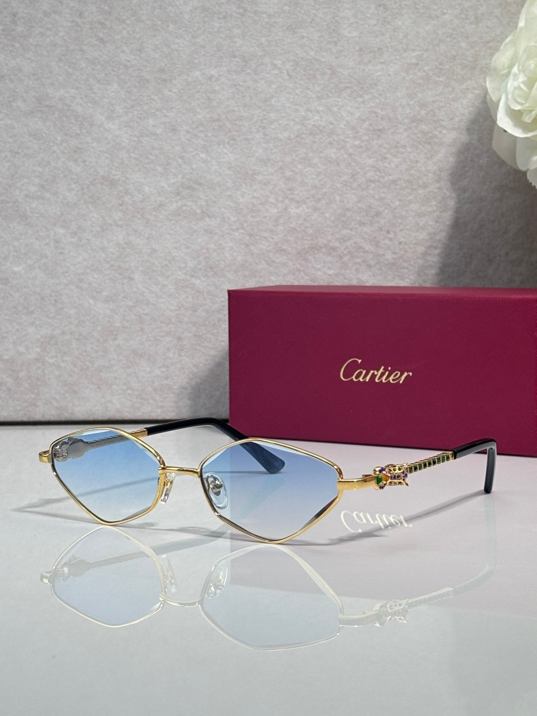 Cartier glasses with gold-tone frame, blue lenses, and black temple tips.