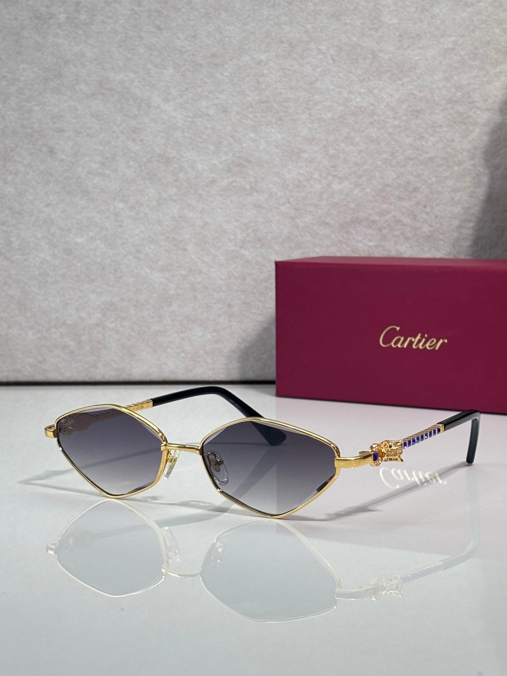 Cartier glasses with gold-tone frame, dark lenses, and blue temple detail.