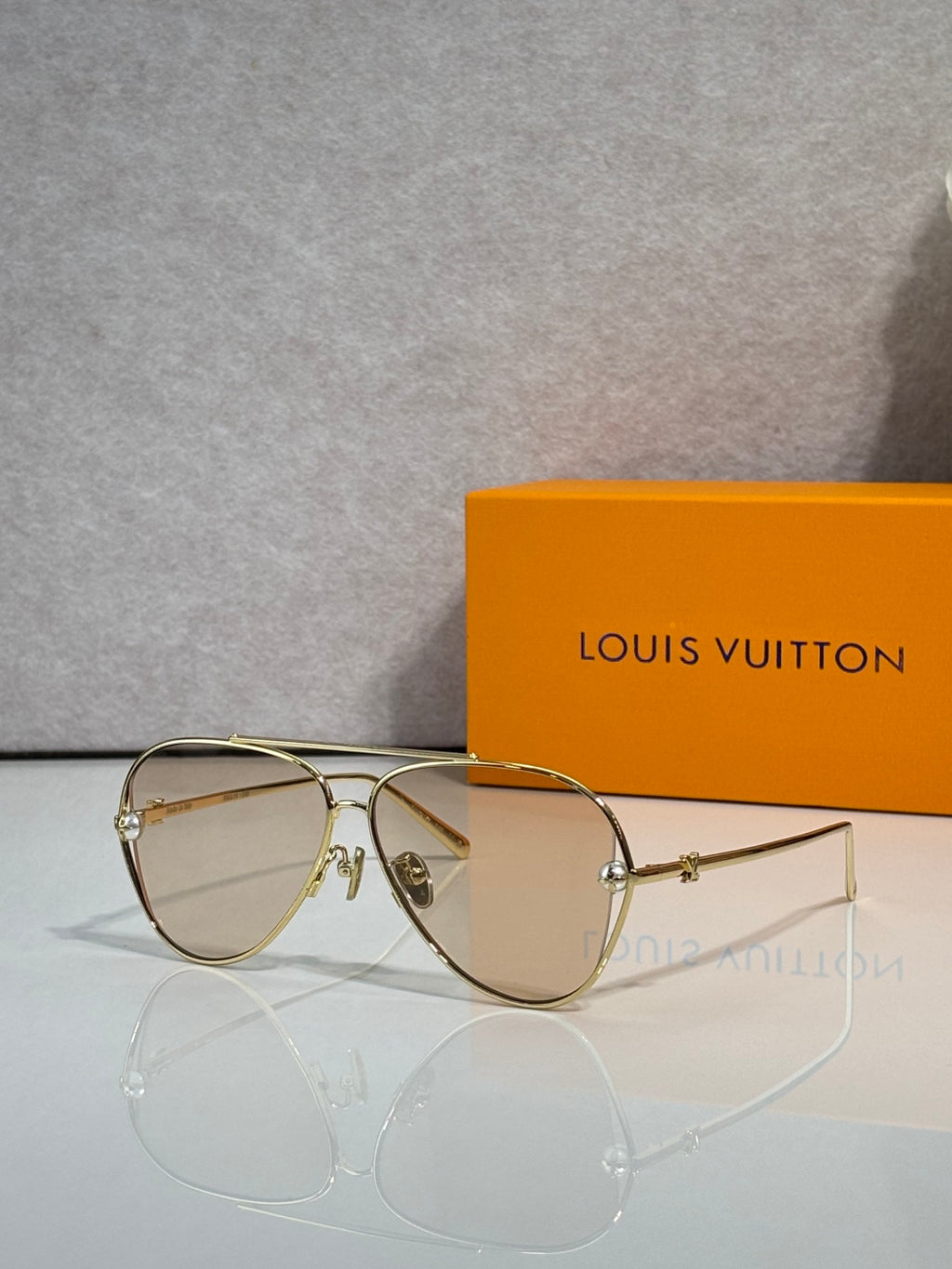 Louis Vuitton sunglasses with beige tinted lenses and gold metal frame, side angle