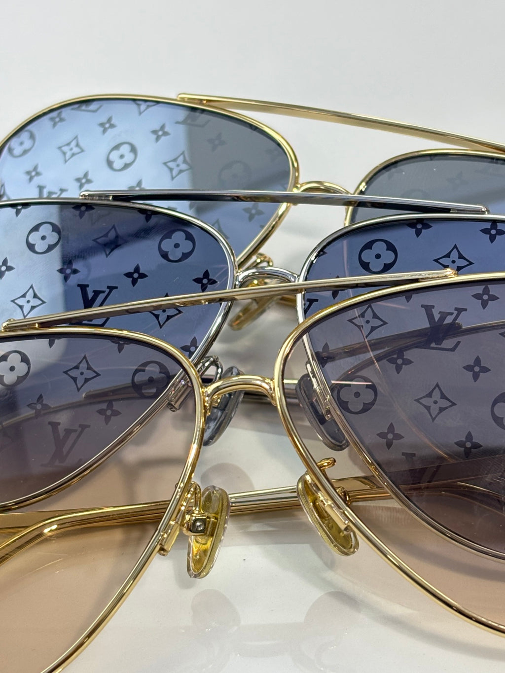 Louis Vuitton sunglasses close-up with blue monogram-pattern lenses and gold frame
