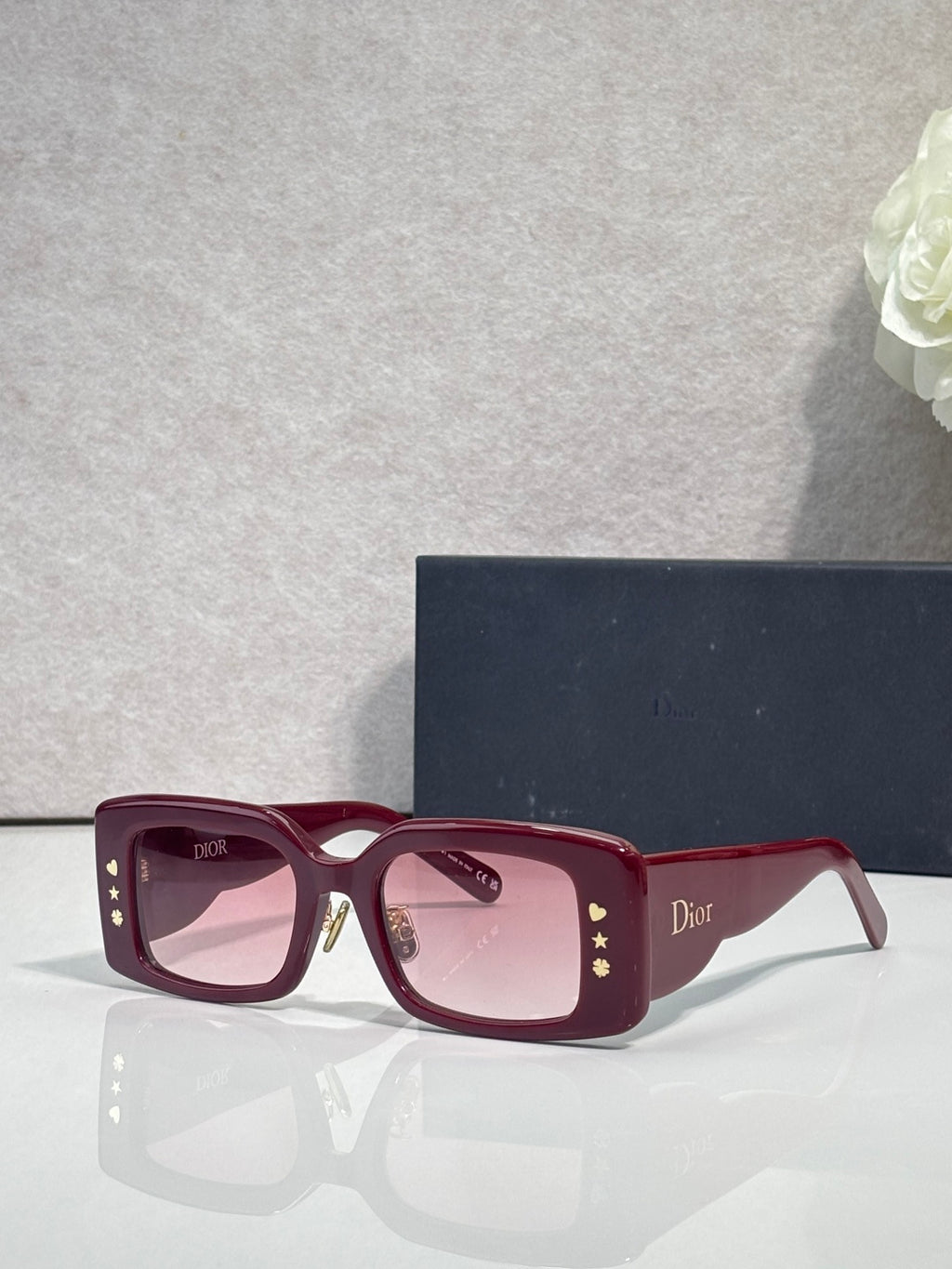 Dior rectangular sunglasses with pink-tinted lenses, burgundy frame, gold star temple detail