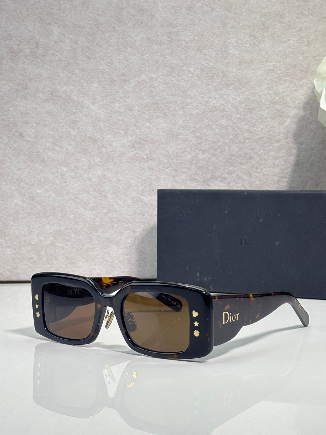 Dior rectangular sunglasses with dark lenses, navy frame, gold star detail at temples