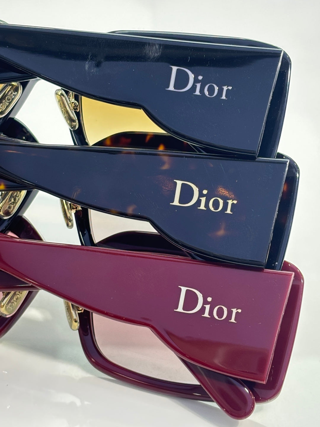 Stacked Dior eyeglass frames with dark lenses and burgundy frame, plus logo cases