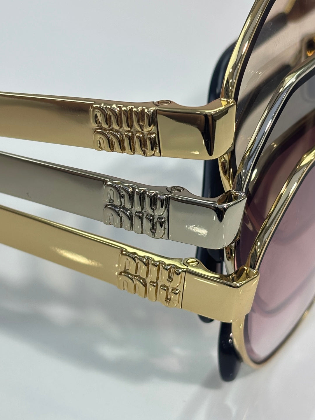 MiuMiu sunglasses close-up of gold temples with engraved logo details