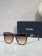 Chanel sunglasses with dark navy frames, tortoiseshell arms, and gold CC logo.