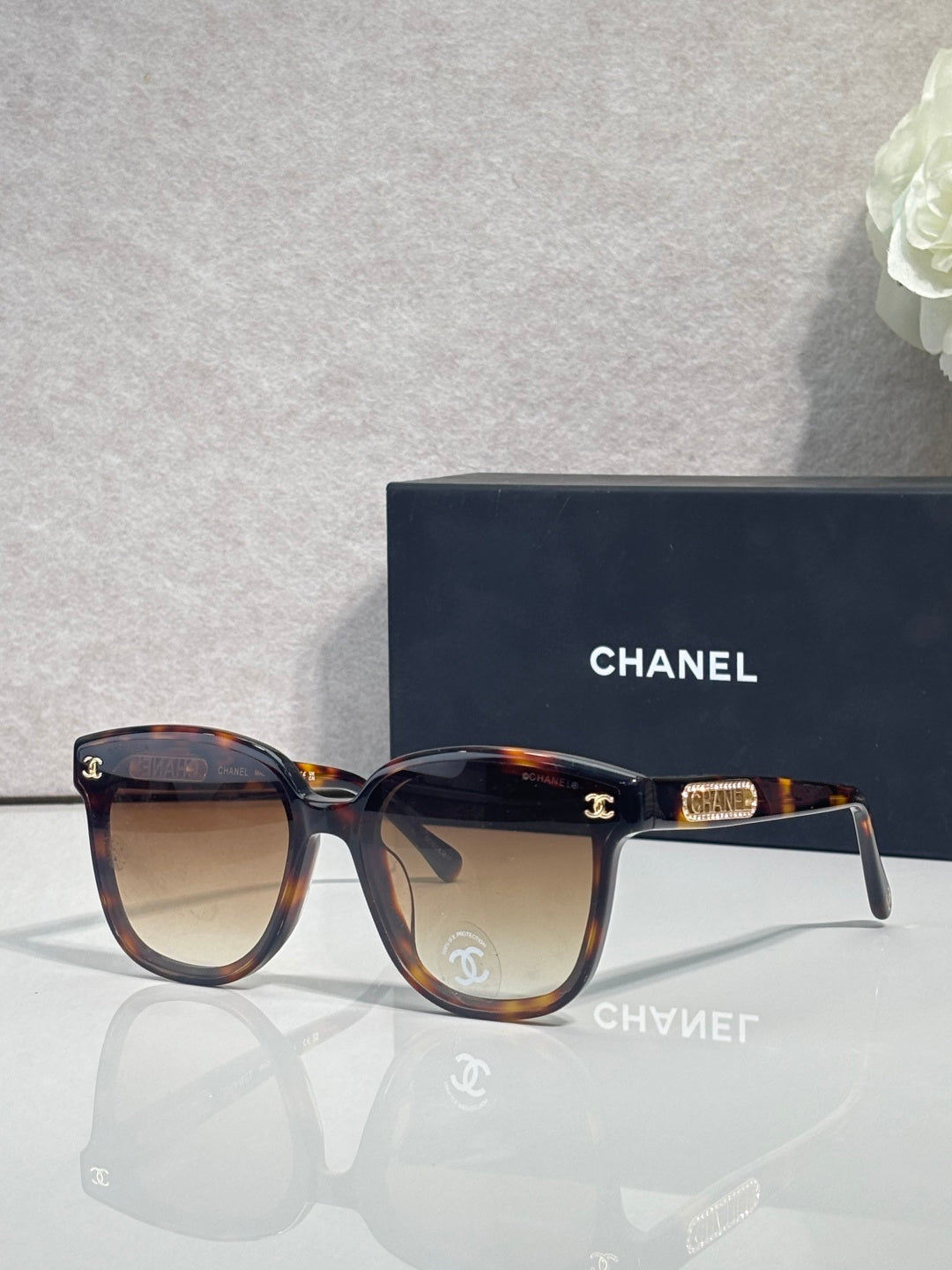 Chanel sunglasses with dark navy frames, tortoiseshell arms, and gold CC logo.