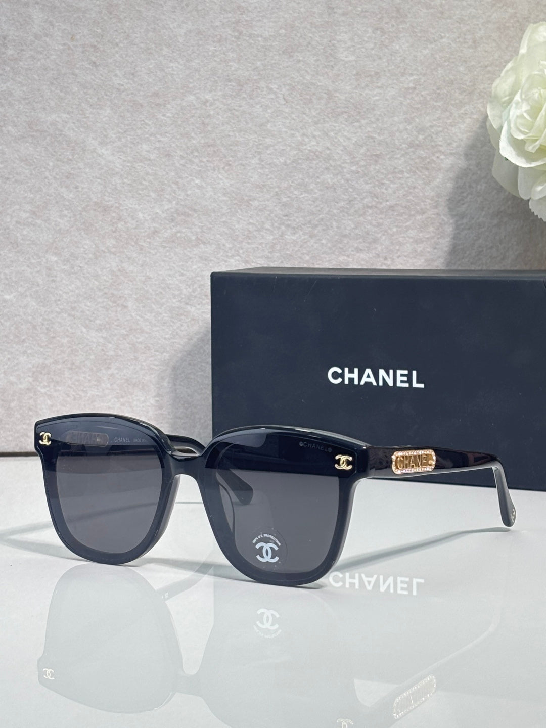 Chanel sunglasses with dark navy frames and gold CC logo on the temple.