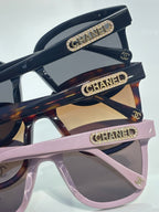 Chanel sunglasses with black and pink frames and gold CHANEL bar logos on the arms.