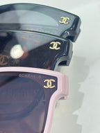 Chanel sunglasses close-up: dark navy and pink frames with gold CC logos.