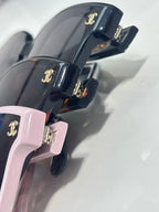 Chanel sunglasses close-up of pink and navy temples with gold CC logo hardware.