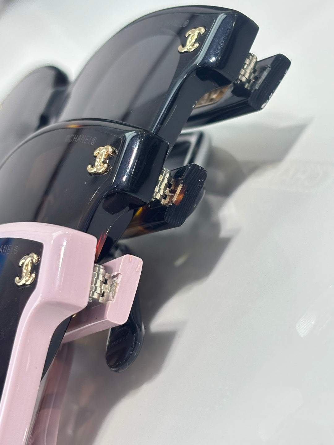 Chanel sunglasses close-up of pink and navy temples with gold CC logo hardware.