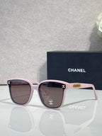 Chanel sunglasses with pink frames, brown lenses, and a gold CC logo on the temple.