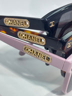 Chanel sunglasses temple close-up with gold CHANEL bar and CC emblem detail.