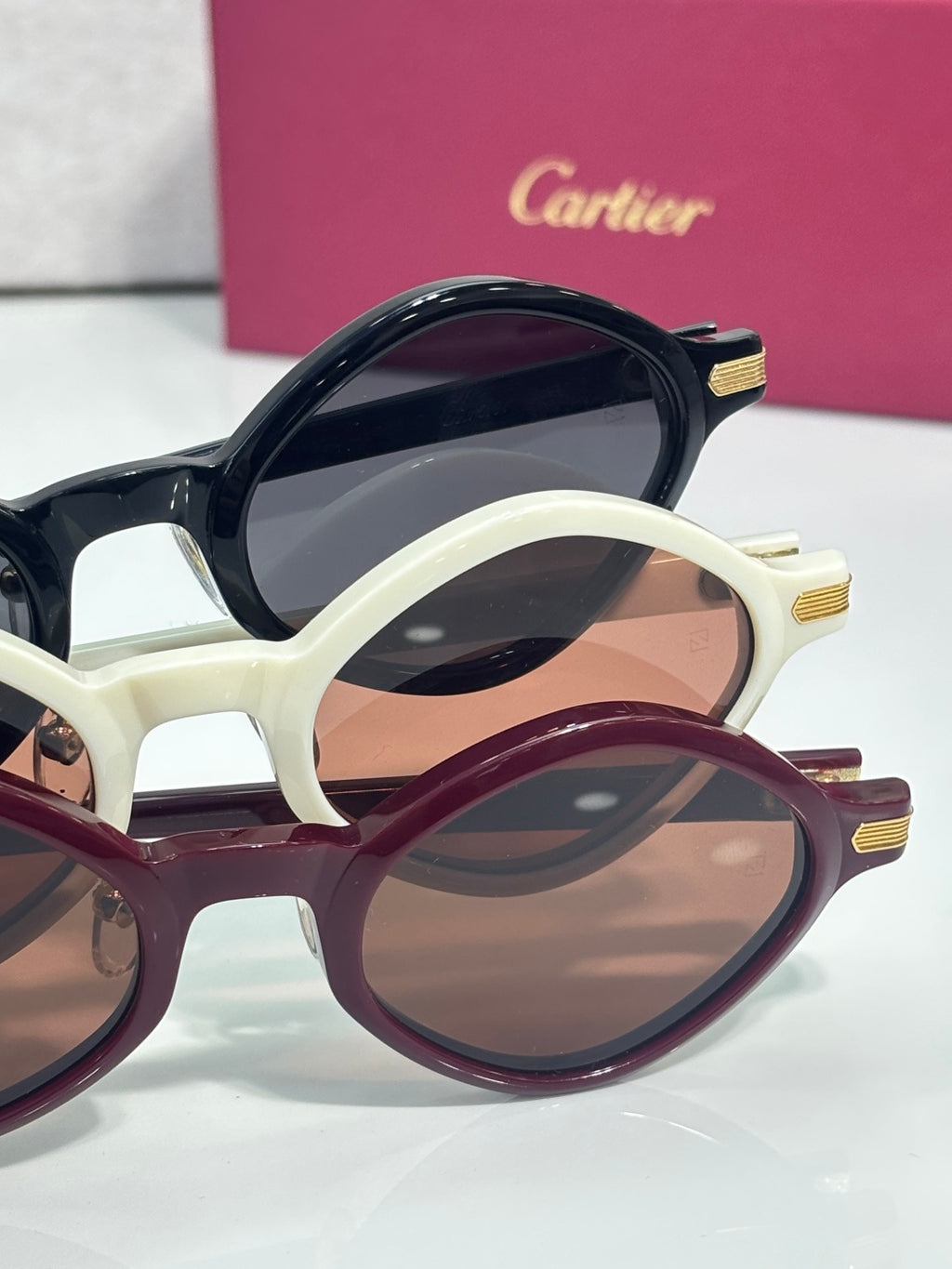 Two pairs of round eyeglasses with cream and burgundy frames, tinted lenses