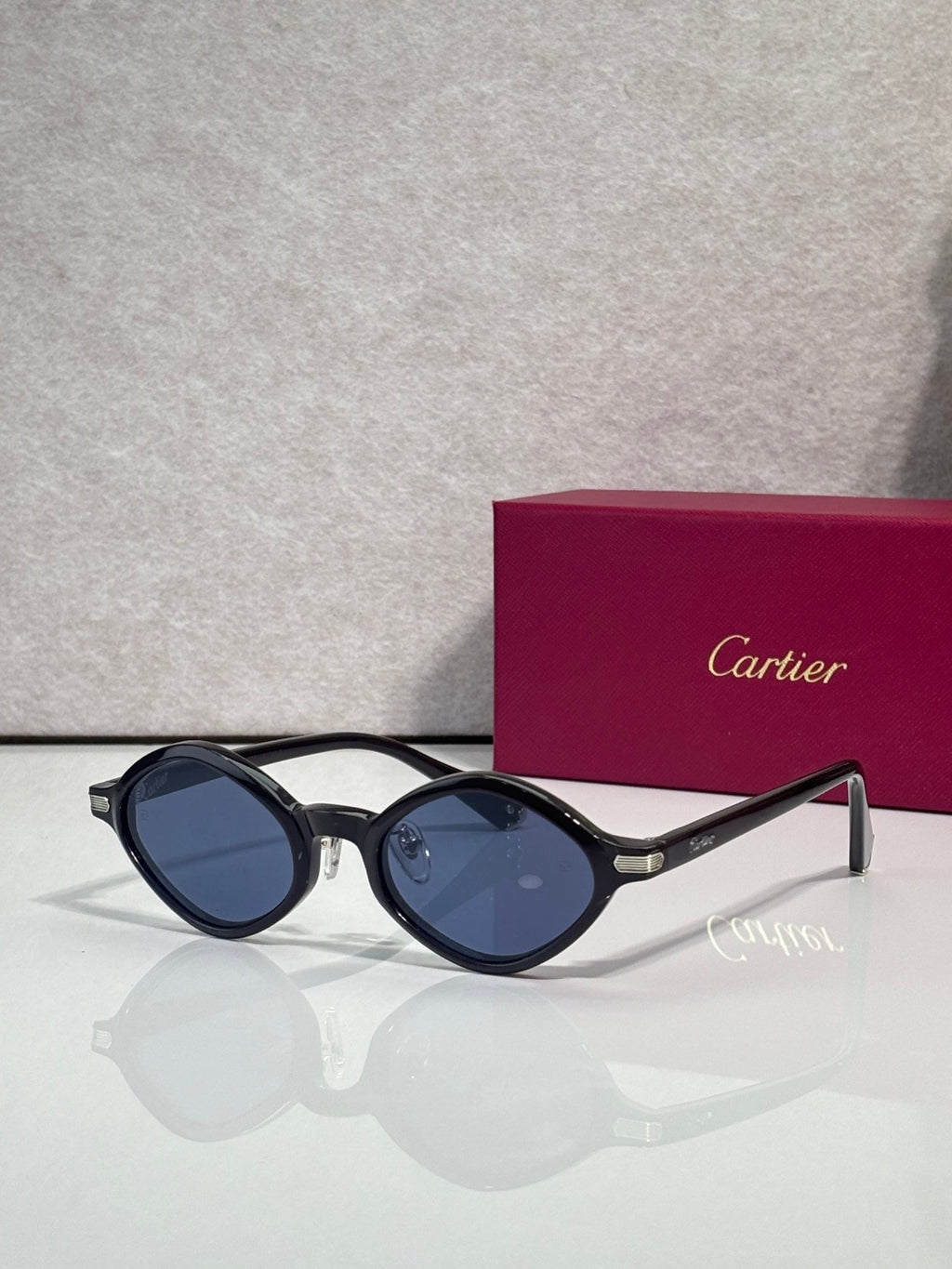 Cartier round sunglasses, dark frames with blue lenses, gold accents at the temples