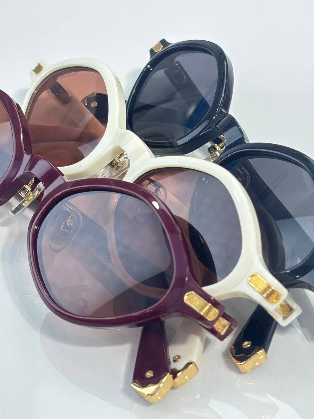 Cartier sunglasses top view, white, navy, and burgundy frames with gold hinge accents