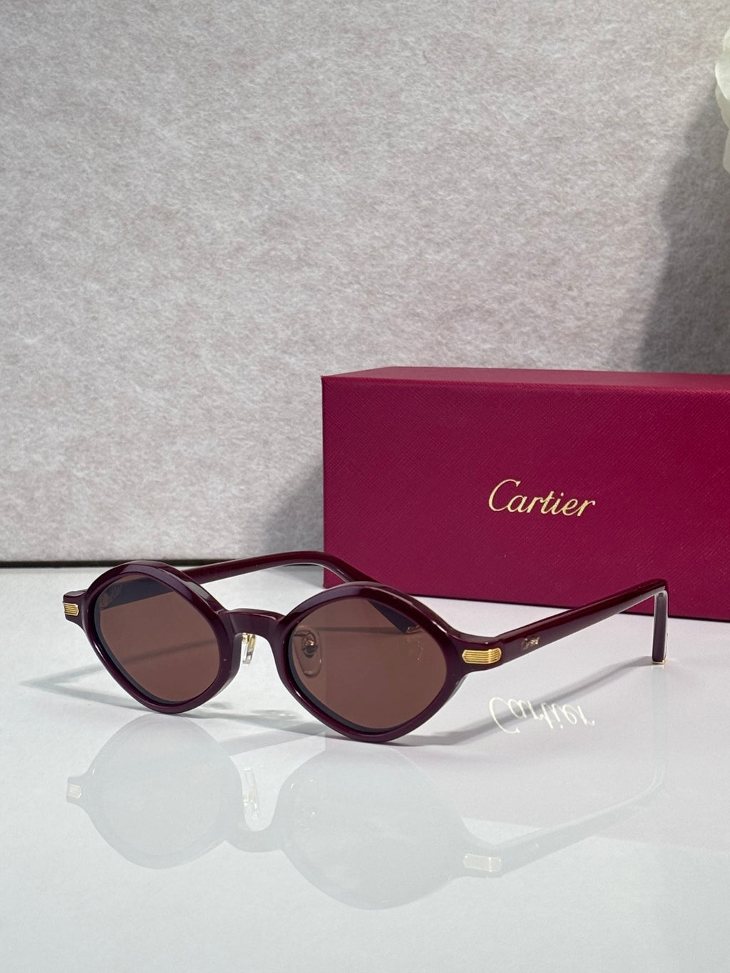 Cartier round sunglasses, burgundy frames, brown tinted lenses, gold detail at temples