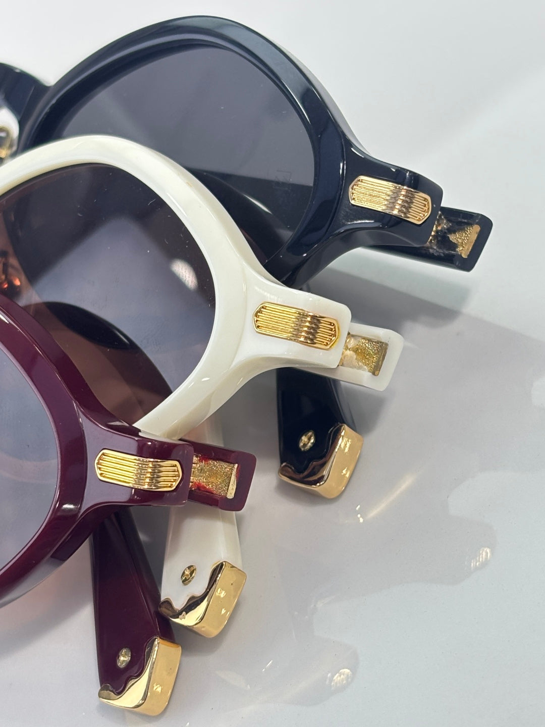 Cartier sunglasses close-up, navy, cream, and burgundy frames with gold hinge details