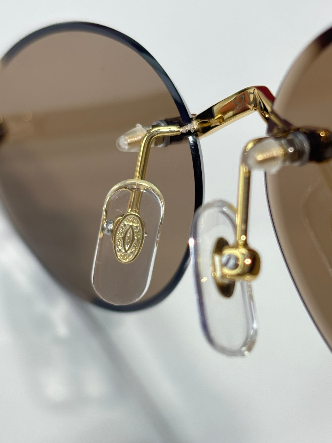Gold eyeglasses close-up with oval logo charm and dark frame edge