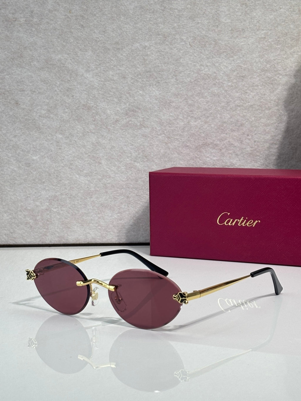 Burgundy-tinted round sunglasses with gold accents and black temples