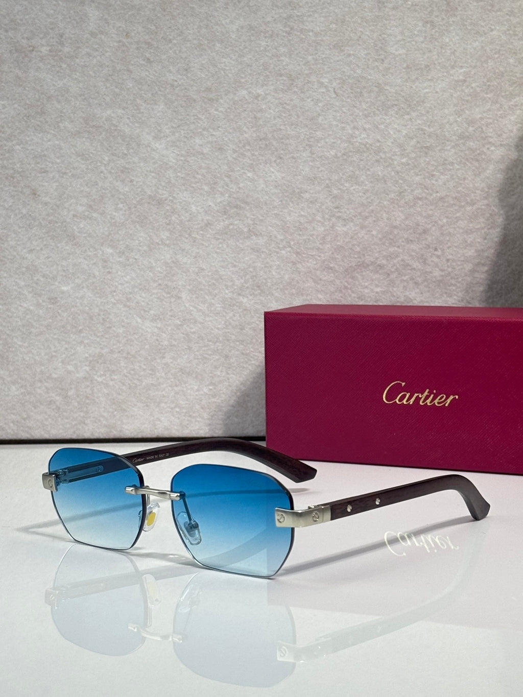 Cartier sunglasses with light blue lenses, dark frame, gold-tone accents