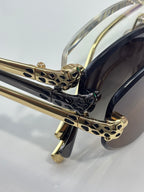 Cartier sunglasses close-up of ornate gold bridge and hinge details, dark lenses