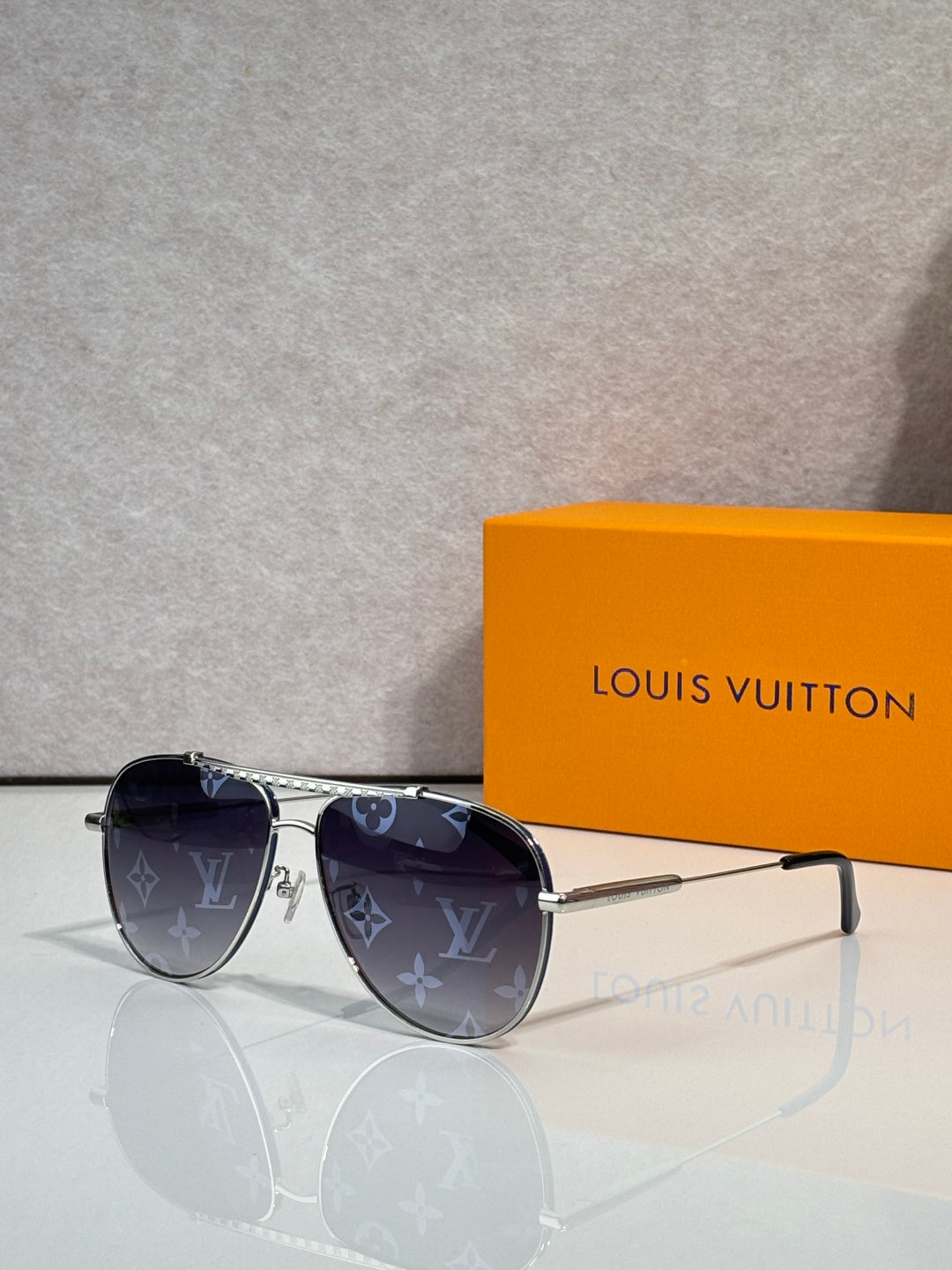 Louis Vuitton sunglasses with dark lenses and blue monogram-pattern frames, gold-tone hardware.