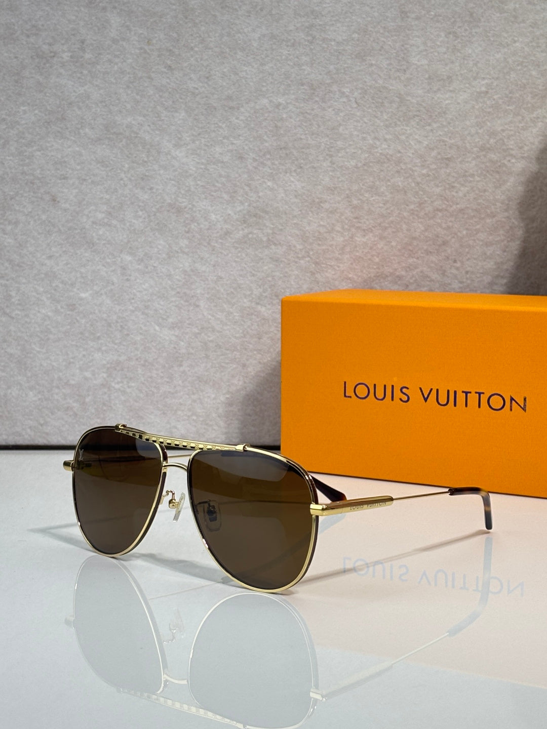 Louis Vuitton sunglasses with dark brown lenses and gold-tone aviator-style frames.