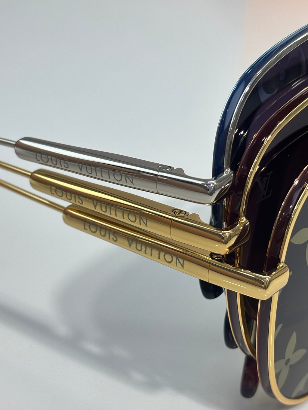 Louis Vuitton sunglasses close-up of gold-tone temple hinge and engraved arm lettering.