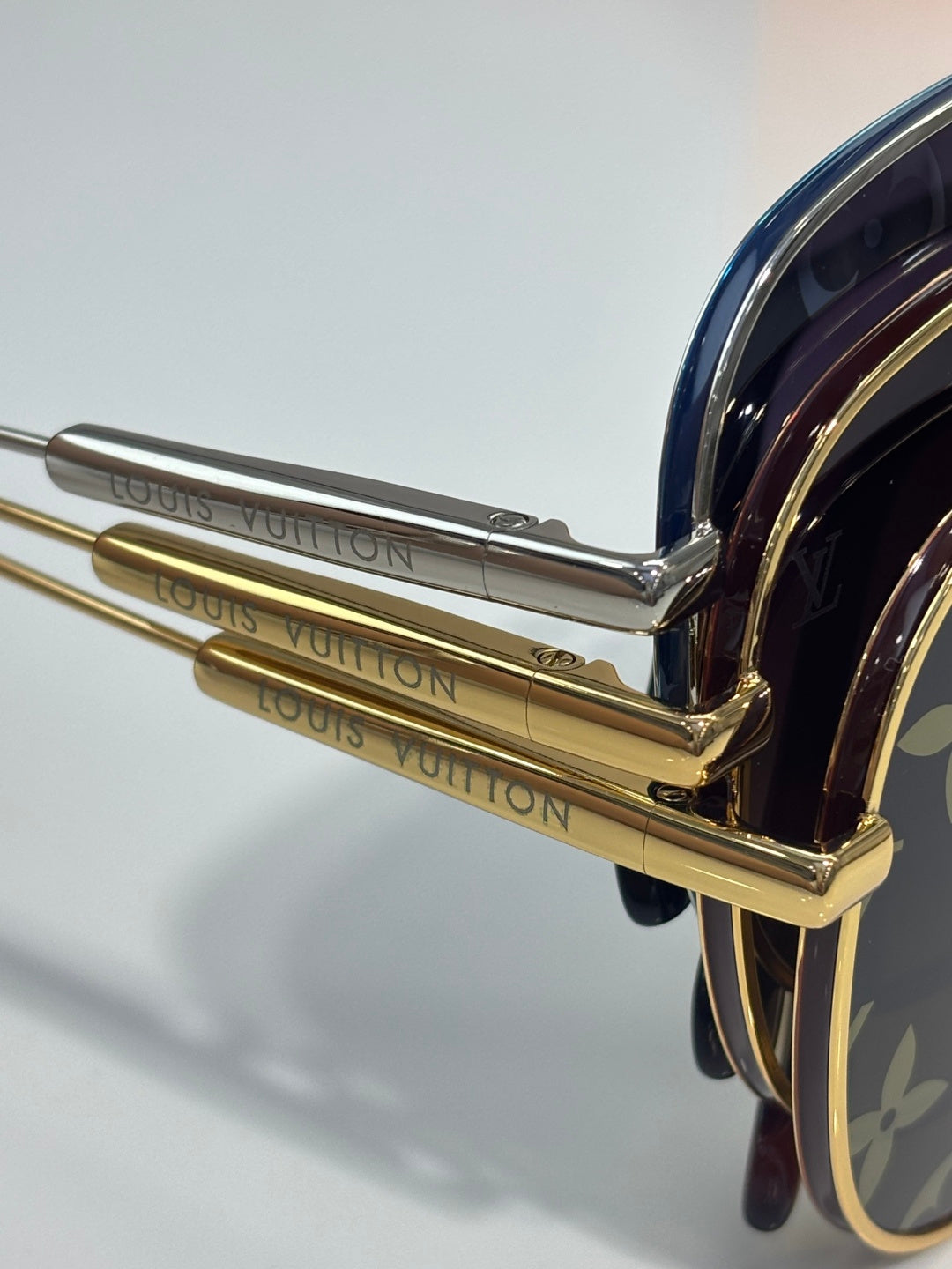 Louis Vuitton sunglasses close-up of gold-tone temple hinge and engraved arm lettering.