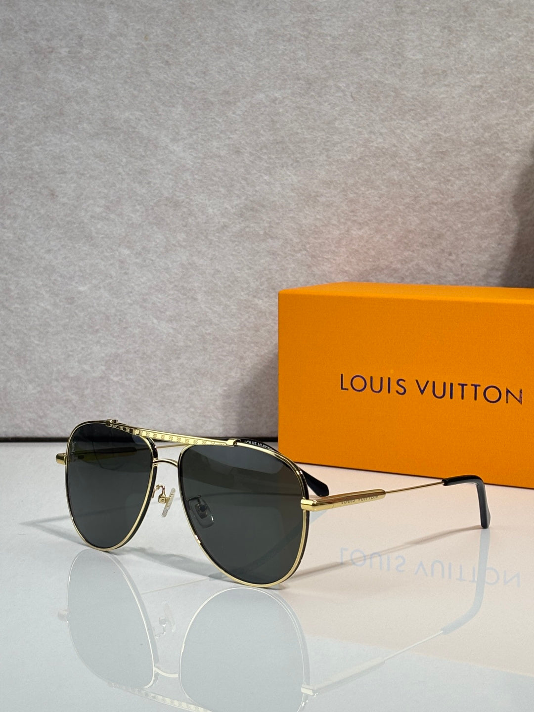 Louis Vuitton sunglasses with dark lenses and gold-tone round frames, side profile view.