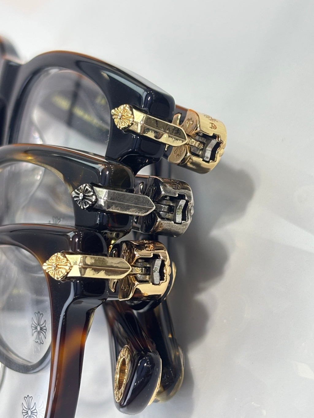 Eyeglasses frame close-up with dark rims and gold flower hinge details on temple