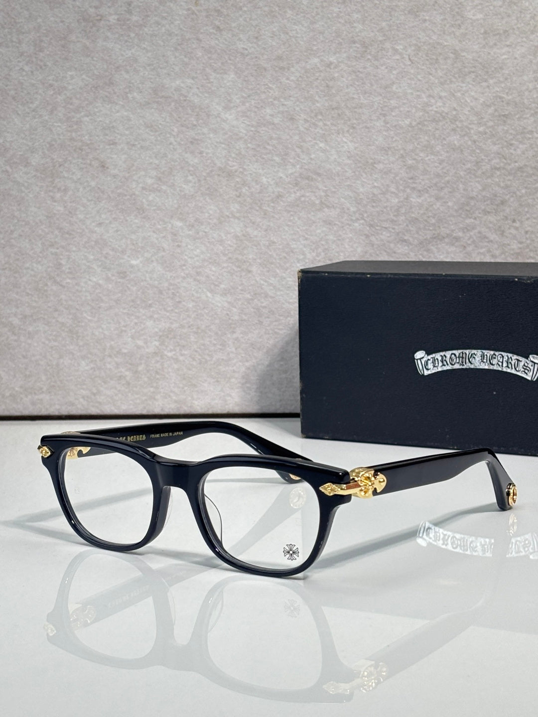 Eyeglasses with dark blue frames and clear lenses, gold bridge and temple accents