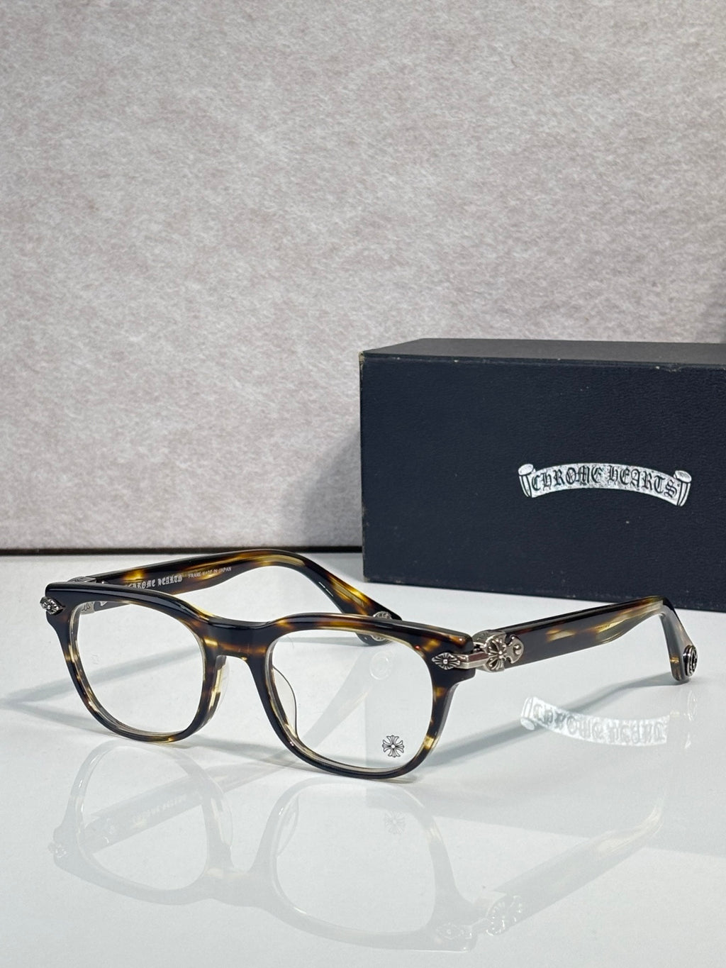 Eyeglasses with tortoiseshell frames and clear lenses, gold bridge detail and hinge