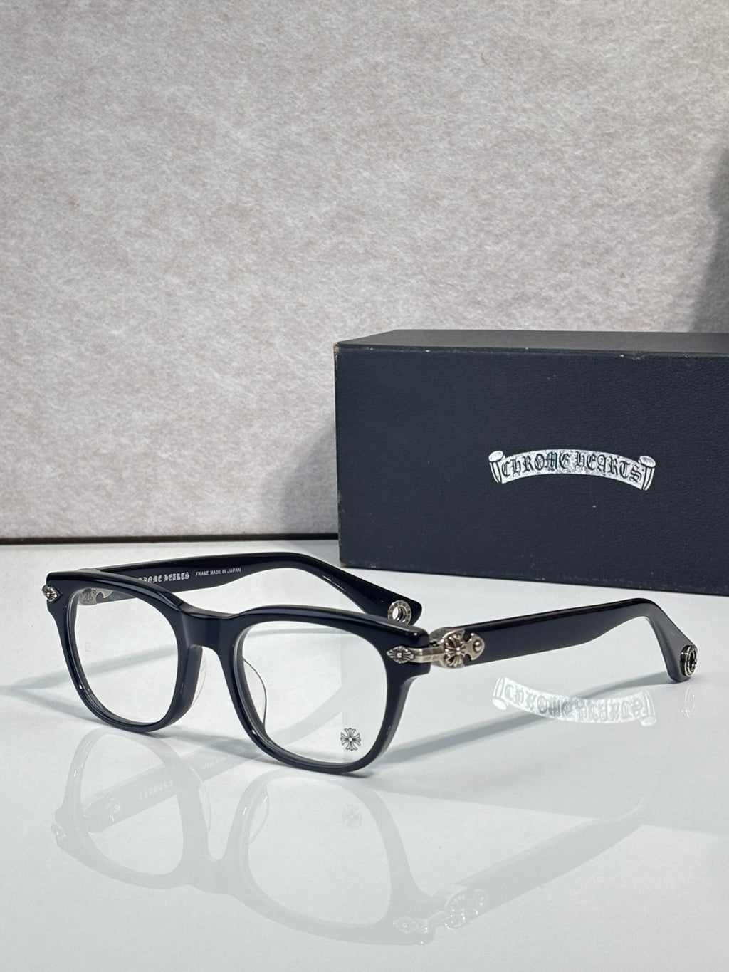 Eyeglasses with dark blue frames and clear lenses, gold accents at the hinge and bridge