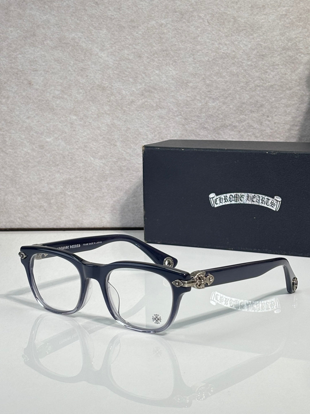 Eyeglasses with dark blue frames and clear lenses, gold hinge hardware and round bridge