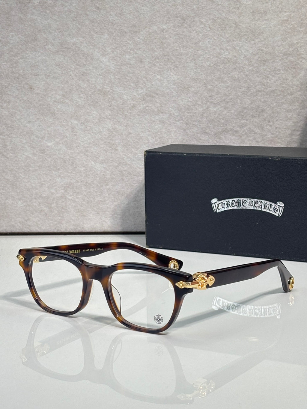 Eyeglasses with tortoiseshell frames and clear lenses, gold bridge ornament and temples