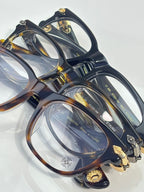 Eyeglasses pair, dark and tortoiseshell frames with clear lenses and gold decorative hinges