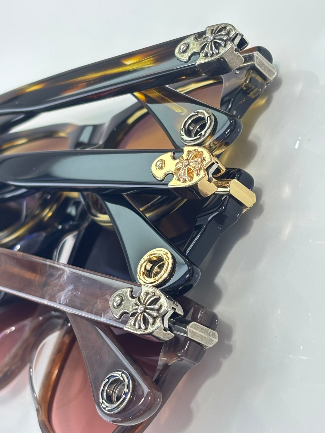 Close-up of sunglasses temples with engraved metal charms in gold and silver