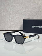 Dark blue sunglasses with gray lenses and gold-tone bow detail at the temples