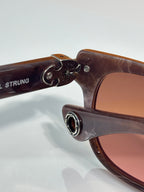Brown sunglasses with engraved metal emblem on the temple near the hinge