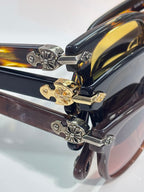 Close-up of tortoiseshell sunglasses temples with gold and silver floral charms