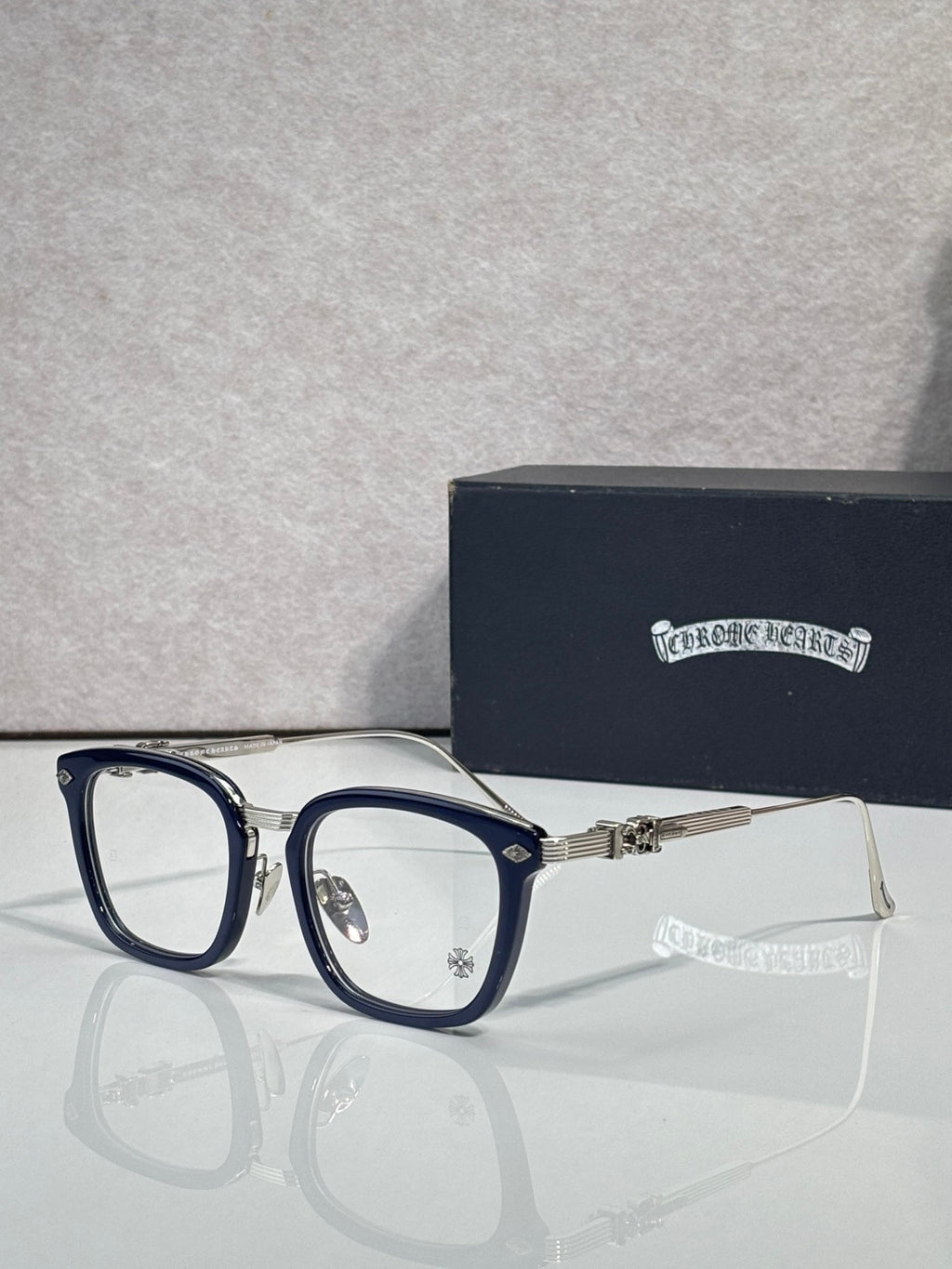 Dark blue eyeglasses with rectangular clear lenses and metal hinge hardware